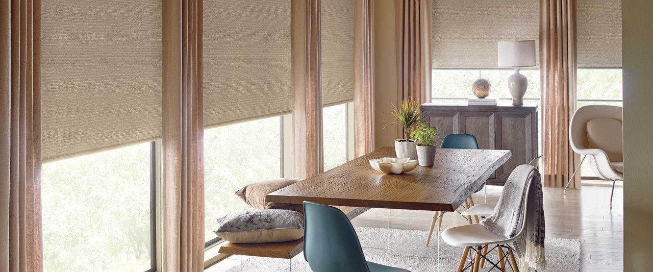 Dining room table with Designer Roller Shades over windows.